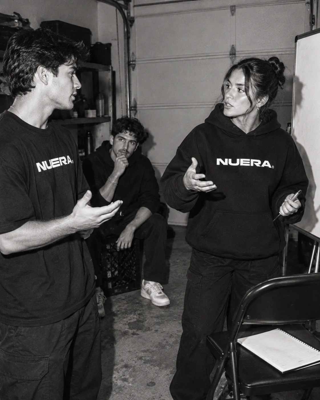 Three adults practicing a conversation in NUERA hoodies and an oversized tee.