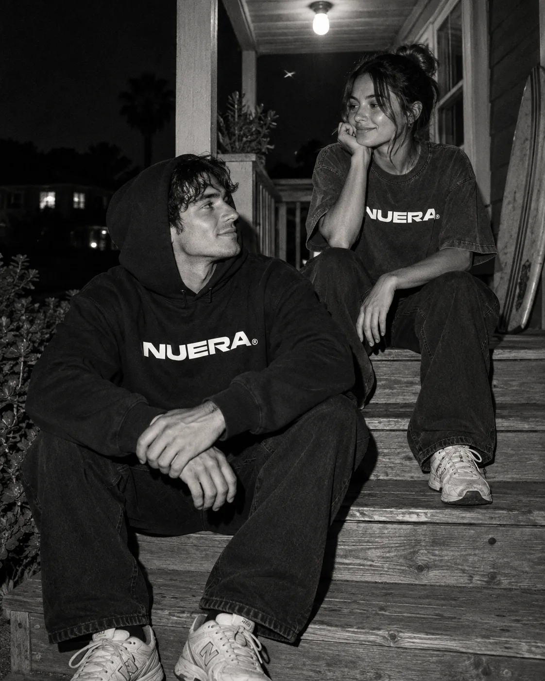 Two friends in NUERA clothing talking on a porch after dark.